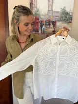 Camisa de manga larga color verde militar, con cuello clásico y cierre frontal de botones. Presenta un canesú bordado con diseño ornamental en la parte frontal superior.