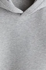 Canguro de efecto neopreno color gris, con capucha de doble capa, hombros caídos, bolsillo canguro frontal y puños y bajo anchos acanalados. De corte holgado.