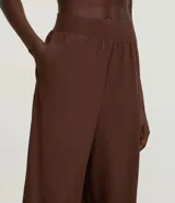 Pantalón deportivo de corte recto y holgado, color marrón, con cintura ancha elástica y pliegues frontales.