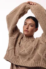 Sweater de tejido de punto grueso con diseño de rombos en relieve, cuello redondo y mangas largas amplias. Presenta una silueta relajada y holgada.