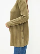 Remera verde oliva de tejido de punto acanalado, con cuello redondo y mangas largas. Detalle de botones en el lateral.