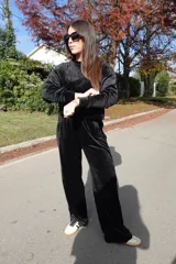 Conjunto de dos piezas confeccionado en tejido plush aterciopelado color negro. Incluye un buzo de corte cropped con cuello redondo y mangas largas, y un pantalón estilo cargo de silueta holgada con bolsillos laterales funcionales y puños ajustables en los tobillos.