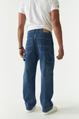 Jean estilo carpenter de corte relajado, recto y amplio, con diseño de cinco bolsillos y costuras reforzadas características del modelo. Presenta un acabado lavado en tono gris oscuro.