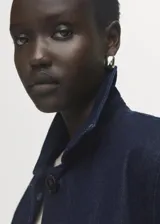Chaqueta de algodón estilo denim en color azul oscuro, con cuello camisero, bolsillos de parche con solapa en el pecho y cierre frontal con botones.