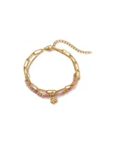 Pulsera doble dorada de acero quirúrgico con baño de oro 18k, compuesta por una cadena de eslabones oblongos y otra cadena fina decorada con cuentas de piedra natural rosada y pequeñas esferas doradas, con un dije colgante en forma de flor.