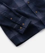 Camisa de franela a cuadros en tonos de azul marino y gris oscuro, con corte regular, manga larga, cuello camisero, cierre frontal de botones y un bolsillo en el pecho.