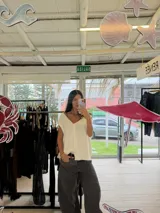 Chaleco de punto color crema con escote en V y cierre frontal con botones. Presenta un diseño sin mangas y corte holgado.