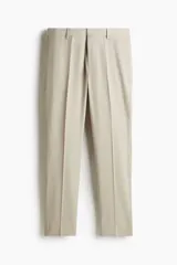 Pantalón de traje beige de corte slim fit, con cierre frontal con cremallera y corchete oculto, trabillas para cinturón, bolsillos laterales y bolsillos traseros ribeteados. Cuenta con raya marcada al frente.
