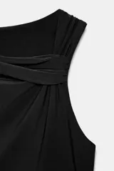 Body negro de escote asimétrico y manga sisa. Presenta un drapeado en el delantero y cierre inferior con botones a presión.