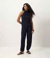 Pantalón largo femenino texturizado color azul marino, modelo aladim, con volumen amplio en las piernas y estrechamiento en el ruedo. Posee cintura elástica incorporada y pliegues delanteros.