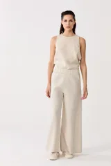 Pantalón de lino color beige, de cintura alta con elástico, bolsillos laterales y corte palazzo.