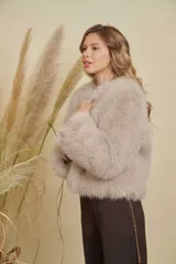 Abrigo corto de piel sintética en tono beige, con cuello redondo y mangas largas. Diseño de corte recto y textura suave.