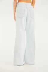 Pantalón de jean color celeste claro, de tiro medio con presillas para cinturón y cierre frontal con botón y cremallera. Presenta diseño de pernera amplia tipo wide leg, bolsillos delanteros clásicos y costuras decorativas a la altura de las rodillas.