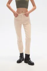 Pantalon de jean recto de tiro alto en color beige, con ruedo deshilachado y cierre frontal con botón y cremallera.