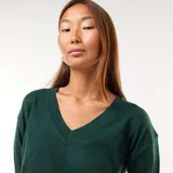 Sweater de punto fino en color verde, con escote en pico y mangas largas con puños acanalados.