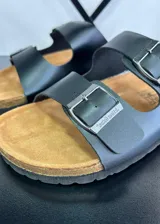 Sandalias negras con plantilla color suela y dos tiras anchas con hebilla metálica ajustable.