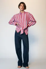 Camisa de manga larga con cuello subido y detalle de lazada frontal. Presenta un diseño de rayas verticales en tonos verde y celeste, con cierre frontal de botones y puños clásicos.