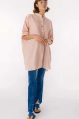 Camisa larga de lino con estampado floral azul sobre fondo beige. Posee cuello mao, mangas cortas con puños, botones metálicos a la vista y tajos laterales en el ruedo.