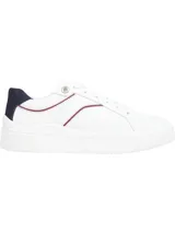 Zapatillas de estilo tenis Tommy Hilfiger, confeccionadas en piel blanca con suela de plataforma de caucho. Presentan detalles en color azul marino en el talón y una línea decorativa en tono granate, junto con ojales metálicos y logo de la marca en el lateral.