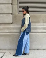 Pantalon de jean de corte wide leg con diseño bicolor, combinando paneles de denim claro en el centro y denim oscuro en los laterales. Presenta ruedo deshilachado y cierre frontal con botón.