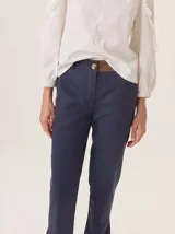 Pantalón de vestir azul marino, corte cigarette con pierna angosta y abertura en el bajo. Presenta costuras en contraste color beige y un botón marrón en la cintura.