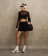 Bermuda deportiva femenina modelo runner, color negro, con cintura elástica ajustable con lazo, bolsillos laterales y aberturas laterales. Confeccionada en tejido de media malla.