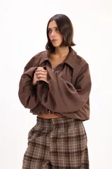 Campera corta de estilo urbano color marrón, con cuello camisero, cierre frontal y mangas abullonadas con puños elastizados.