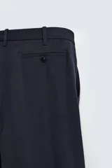Pantalón de corte regular fit confeccionado en tejido ligero de lana de origen italiano. Presenta bolsillos frontales, bolsillos traseros de vivo con botón y cierre frontal con cremallera y botón.
