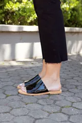 Sandalias bajas negras de cuero charol, con base color suela y diseño minimalista.