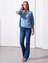 Blusa de manga tres cuartos color celeste claro, confeccionada en lyocell, con escote en V y detalle de frunces en el canesú y puños.