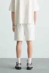 Bermuda de algodón gris con efecto lavado, corte relajado, cintura elástica ajustable con cordón y bolsillos laterales y trasero de vivo.