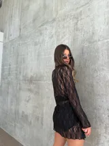 Falda corta de encaje negro con diseño semitransparente y cintura elástica.