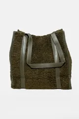 Cartera tipo tote de textura de peluche en color verde oliva, con manijas y detalles de refuerzo en cuero sintético al tono.