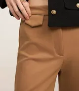 Pantalón de mujer modelo flare, confeccionado en punto roma color marrón, con cintura alta, bolsillos delanteros de solapa, bolsillos traseros embutidos y cierre delantero con cremallera.
