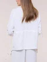 Chaqueta liviana color beige de silueta fluida y diseño abierto, con solapa caída, cintura con cordón ajustable y mangas 3/4 con presilla y argolla metálica.