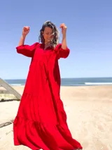 Vestido largo color rojo, con escote en V, mangas 3/4 abullonadas y corte escalonado con volantes.