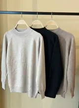 Buzo de punto en color beige, con cuello redondo alto y mangas largas con diseño raglán. Presenta puños y cuello acanalados.