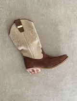 Botas de cuero color marrón y blanco con bordados negros, de estilo cowboy con taco bajo.