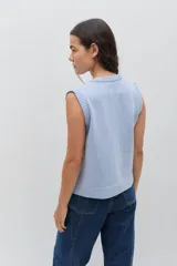 Chaleco de punto color celeste, con diseño de trenzas y pequeñas flores bordadas a mano en color marrón oscuro. Presenta cuello redondo y terminaciones acanaladas.