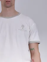 Remera blanca de mangas cortas con cuello y puños en color verde. Estampado frontal con texto y pelotas de tenis.