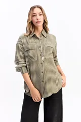 Camisa de manga larga con estampado de rayas verticales en tonos azul y blanco. Presenta cuello clásico, cierre frontal con botones y dos bolsillos tipo cargo en el pecho. Su diseño es de corte relajado y holgado.