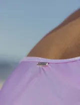 Malla enteriza color lila brillante, de un solo hombro y con abertura lateral con lazos.