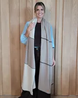 Bufandón de lana lambswool, diseñado para ser utilizado también como ruana. Presenta un diseño de bloques de color en tonos neutros beige y marrón con líneas horizontales oscuras.