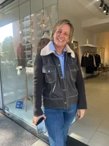 Campera de cuero marrón con cuello de piel sintética, mangas de paño y costuras a la vista en contraste. Presenta cierre frontal con botones metálicos y bolsillos delanteros con solapa.