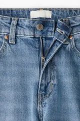 Pantalón de jean celeste de tiro alto, corte ancho y recto, con cinco bolsillos y cierre con botón.