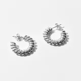 Aros tipo argolla plateados con diseño de espiral.