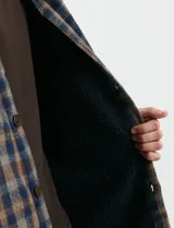 Sobrecamisa de manga larga con diseño a cuadros, cuello camisero y bolsillos laterales. Presenta un interior forrado con textura símil corderito y cierre frontal con botones.