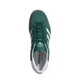 Championes Adidas Gazelle Indoor de gamuza color verde, con las icónicas tres tiras laterales en blanco y suela de caucho color caramelo. Presenta el nombre del modelo en letras doradas y detalle en el talón en color blanco.