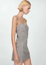 Vestido corto entallado con escote corazón y tirantes finos. Presenta un diseño estampado a cuadros en tonos grises con líneas finas en naranja.