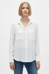 Camisa blanca de manga larga, con cuello en V, cierre frontal de botones y bolsillos frontales con solapa.
